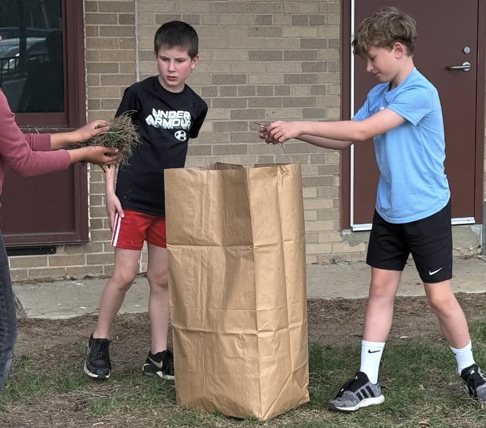 boy-in-blue-shirt-putting-leaves-in-tall-paper-bag