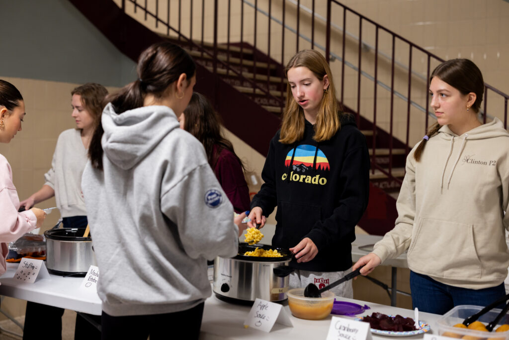 line-of-students-passing-out-food-from-croc-pots
